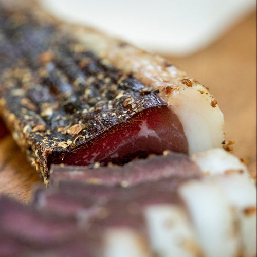 Close-up of a sliced wet biltong with a fat layer, available to buy online.