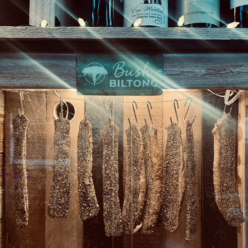 Biltong slabs hanging in a wooden biltong box with 'Bush Biltong' branding.